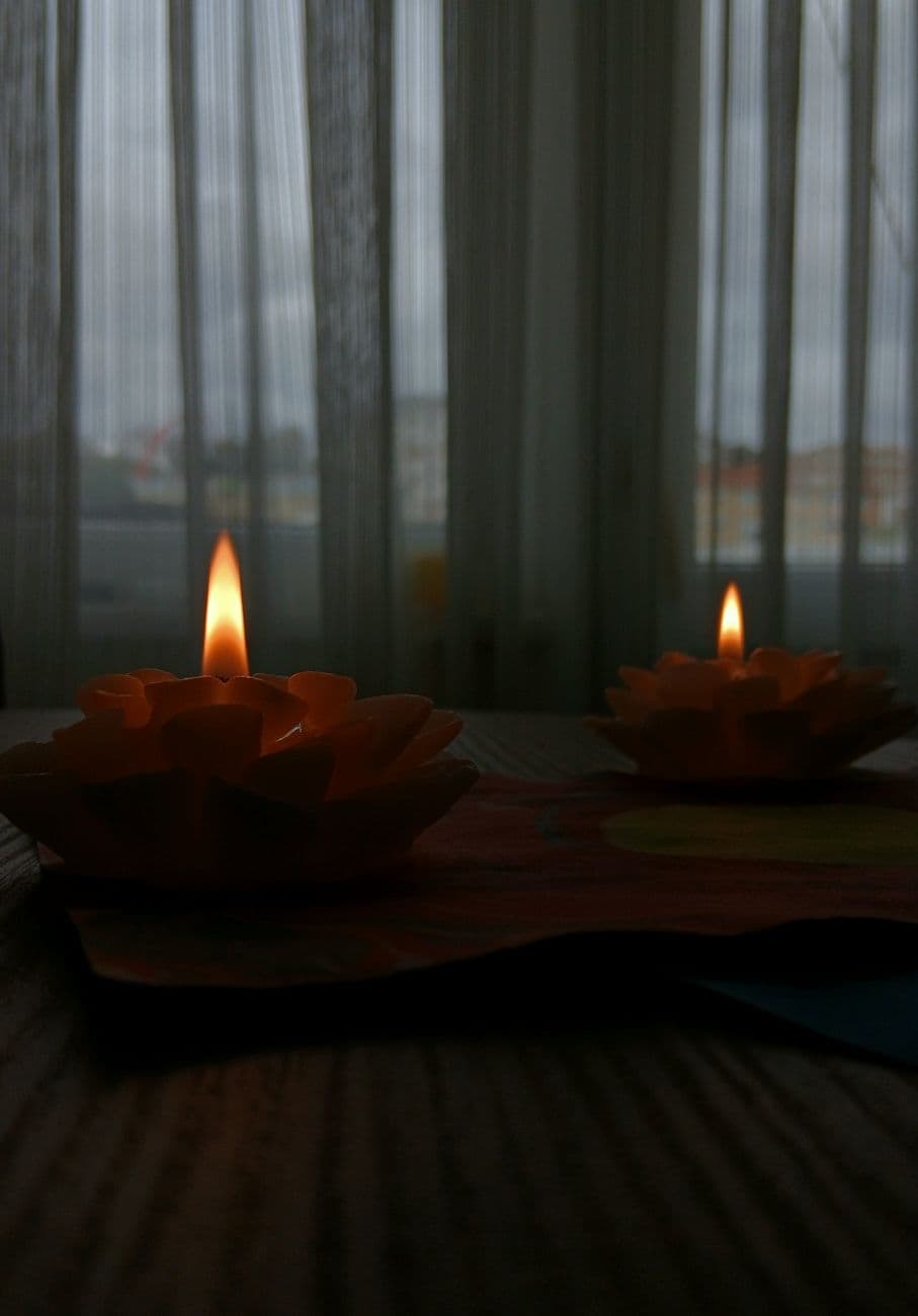 A serene image of decorative candles casting a warm glow indoors on a wooden table.