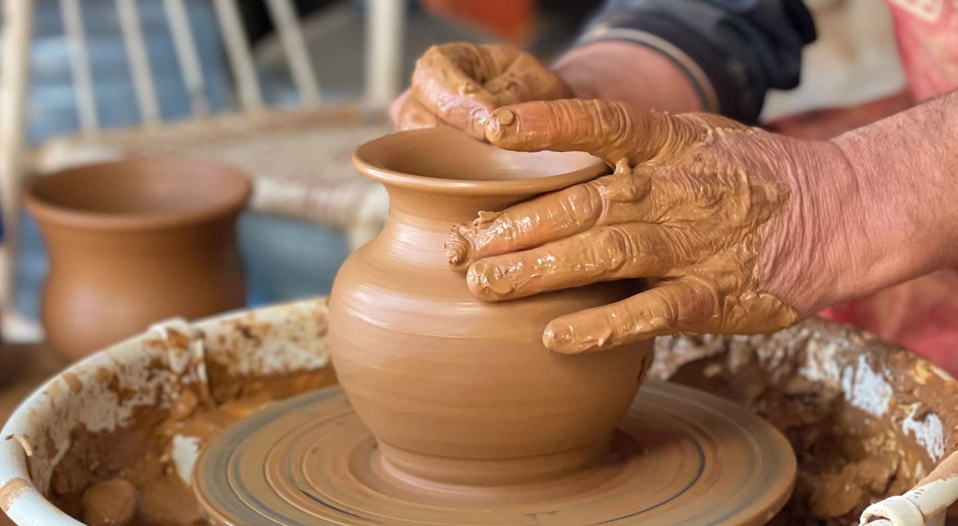 Artisan hands sculpting pottery on a wheel, showcasing the creative process.