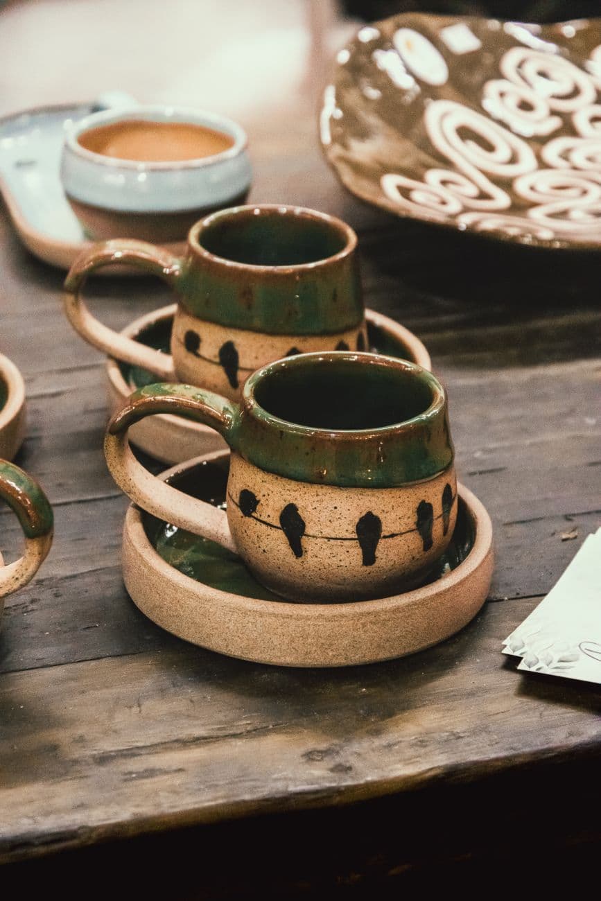 Artisan ceramic cups with earthy design on a rustic wooden table.