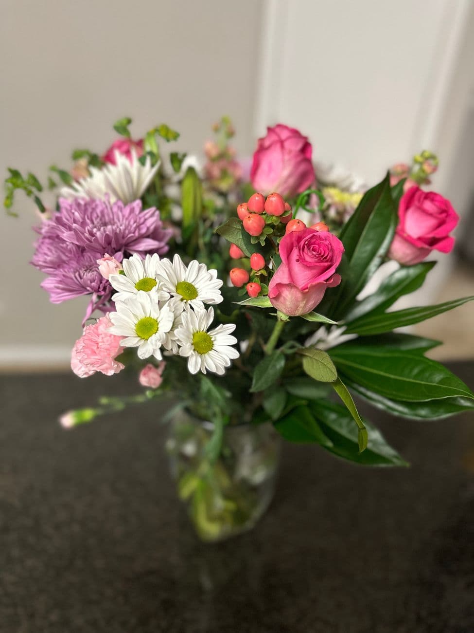 Colorful bouquet featuring pink roses, daisies, and greenery in a vase. Perfect for home decor.
