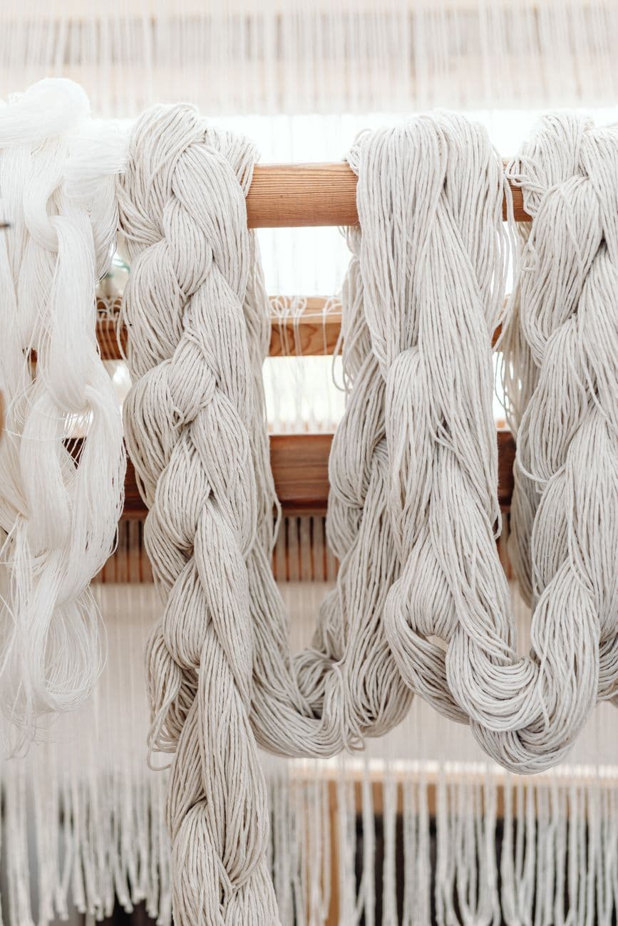 Close-up of braided cotton yarn hanging on a wooden loom, perfect for textile crafts.